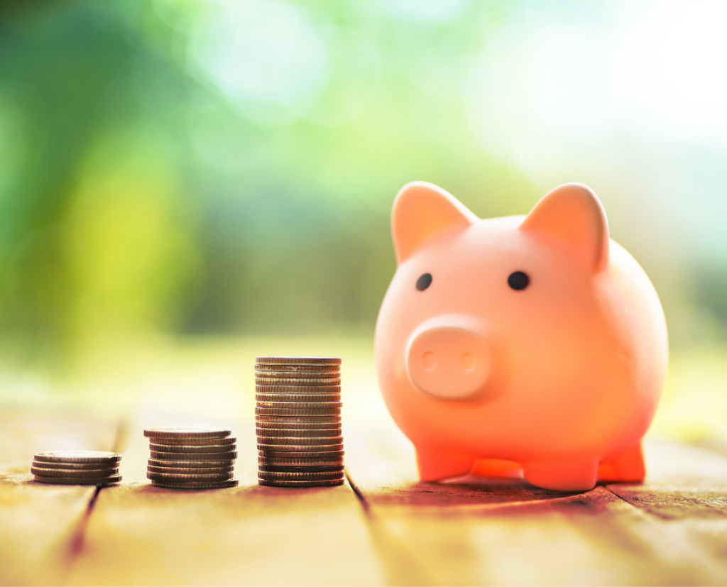 Piggy bank next to stacks of coins symbolizing saving money.