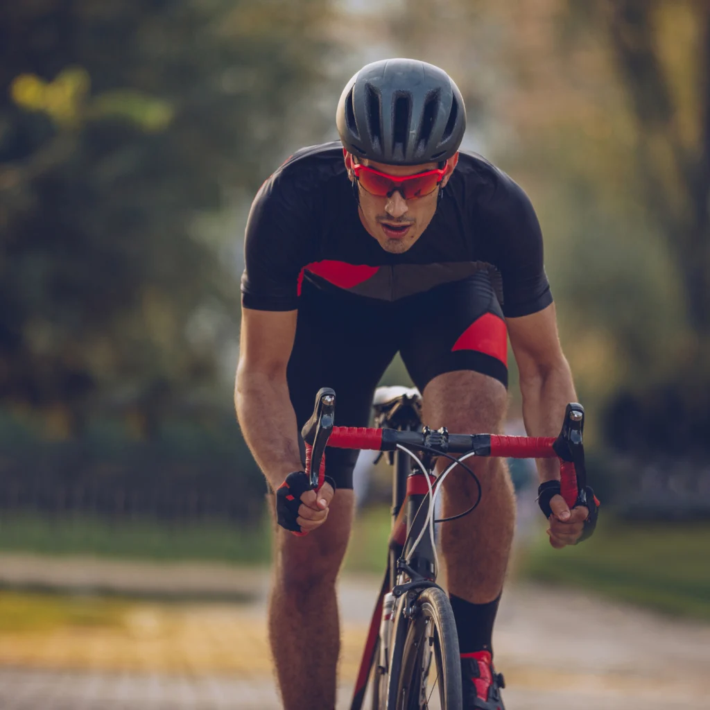 Cyclist in helmet and sunglasses riding road bike intensely.