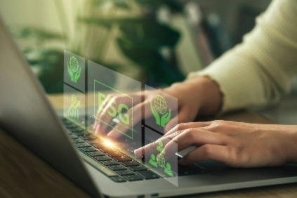 Hands typing on laptop keyboard with futuristic green digital icons overlay.