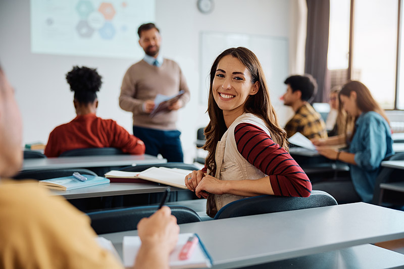 Student smiling at camera during interactive classroom lecture session.